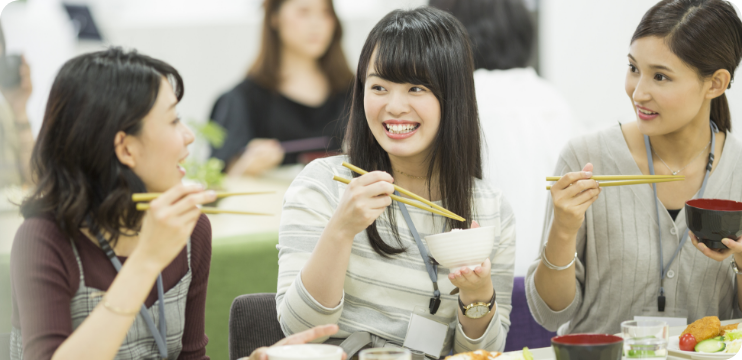 社員食堂で同僚とランチを楽しむ女性たち