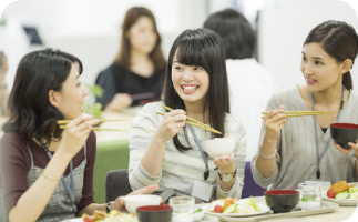 社員食堂で同僚とランチを楽しむ女性たち